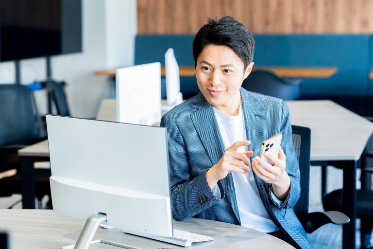 オフィスでスマートフォンを持つ男性