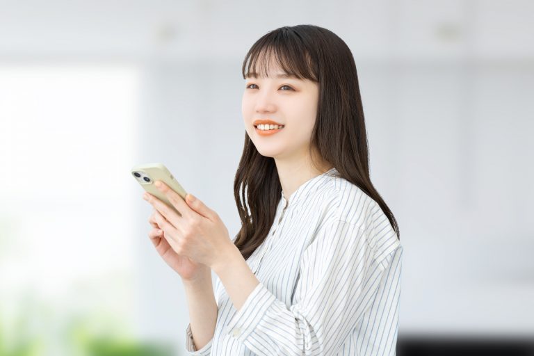 スマートフォンを持って微笑む女性