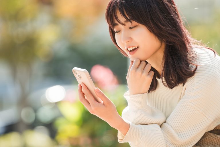スマートフォンを見て微笑む女性