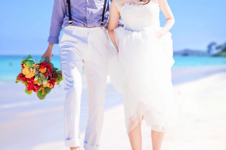 ブーケを持って海辺を歩く新郎新婦